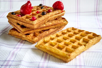 Belgian waffles with berries on a fabric background.