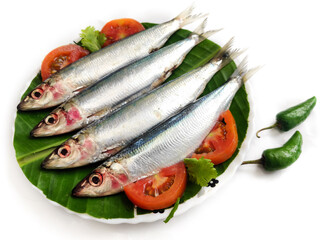 Fresh Slender Rainbow Sardine decorated with vegetables and herbs on a wooden pad.Selective Focus.
