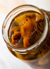 Tasty homemade pickled mushrooms lactarius deliciosus in open jar on table..