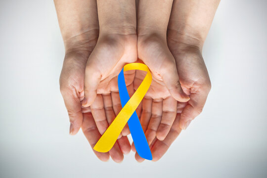 Adult and child hands holding blue and yellow ribbon shaped paper, Down syndrome awareness , World down syndrome day