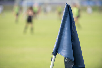 Blue corner flag from a football pitch, seeing group of players together as a team in a background....