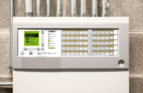 Fire alarm system in trouble. Control panel display with error message, peeping and many orange flickering lights. Fire control panel in electrical room of residential or commercial building.