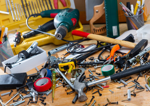 Various fasteners, supplies and hand tools in mess on wooden table. DIY home improvement concept