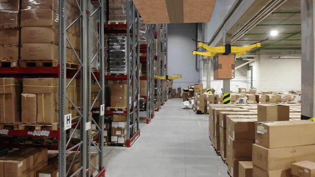 AERIAL. Group of delivery drones flights inside huge warehouse. Drone deliveries a goods. Futuristic concept.