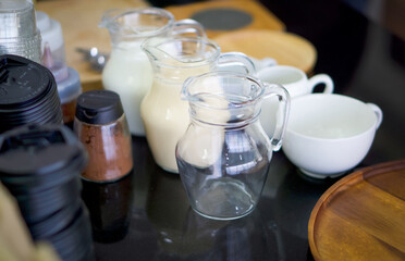 Various essential components for making coffee are placed on the granite countertop. Fresh milk, Condensed milk, Cocoa powder.