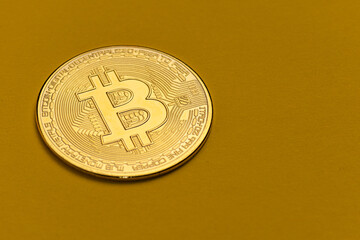 Bitcoin gold color, close-up. against a mustard-colored background