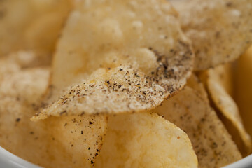 White bowl with organic potato chips sprinkled with fresh ground black pepper