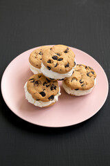 Homemade Chocolate Chip Cookie Ice Cream Sandwich on a pink plate on a black background, low angle view.