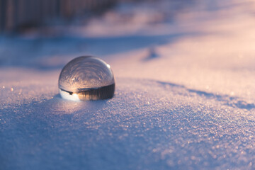 glass transparent ball in the snow in winter, sun rays reflection. severe frost, cold