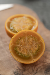 Lulo fruit sliced in halves on olive wood board on kitchen countertop