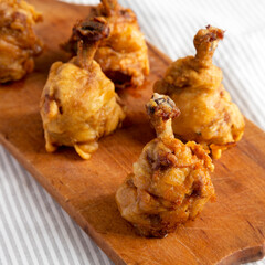 Homemade Spicy Chicken Lollipop on a rustic wooden board, side view. Close-up.