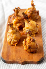 Homemade Spicy Chicken Lollipop on a rustic wooden board on cloth, low angle view.