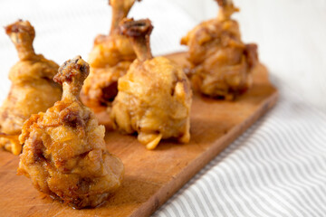 Homemade Spicy Chicken Lollipop on a rustic wooden board on cloth, side view. Copy space.