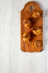 Homemade Spicy Chicken Lollipop on a rustic wooden board on a white wooden surface, top view. Overhead, from above, flat lay. Copy space.