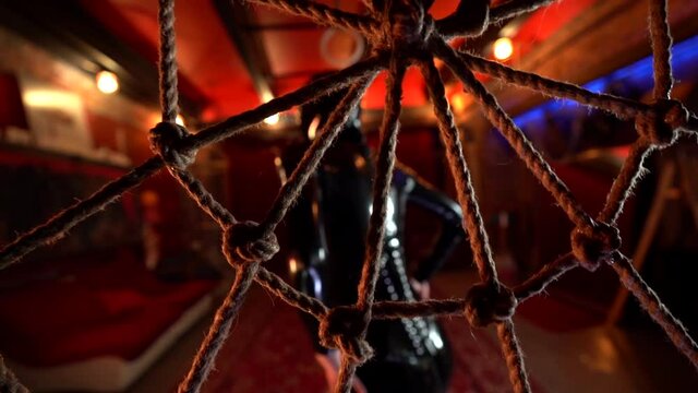 roleplay and bdsm performance, woman in latex suit is dancing in front of web of spider