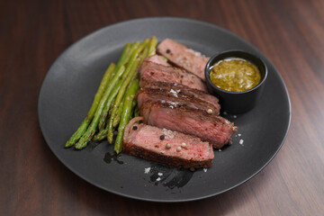 New york steak with asparagus on black plate with pesto