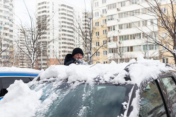man cleans the car from the snow