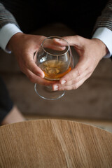 A man businessman holds a glass with alcohol in his hand. Dressed in a jacket and shirt. Rest after a working day