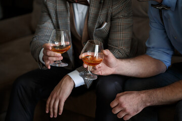 A man businessman holds a glass with alcohol in his hand. Dressed in a jacket and shirt. Rest after a working day