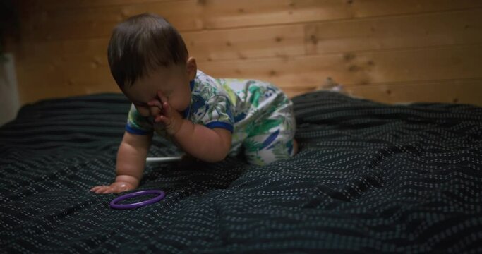 A little baby is crawling on a mattress on the floor in a loft space in the morning