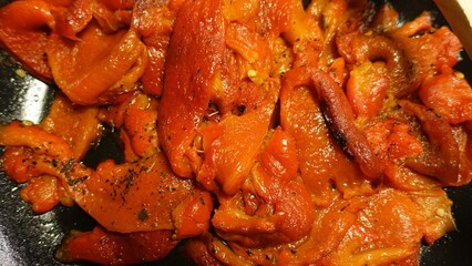 Red peppers in a pan with garlic, oil, parsley.