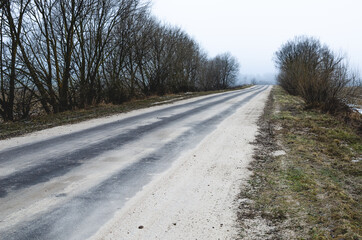 The asphalt road is abundantly covered with sand by road services in case of icing