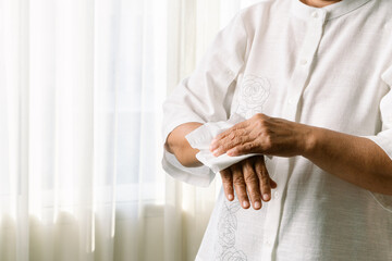 Senior woman cleaning her hands with white soft tissue paper. isolated on a white backgrounds