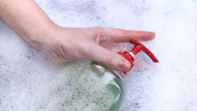 Bottles of detergents float in the foam. The concept of the dangers of household chemicals. Sodium laureate, parabens, sulfates and other chemical compounds in the foam. Liquid soap in a yellow jar