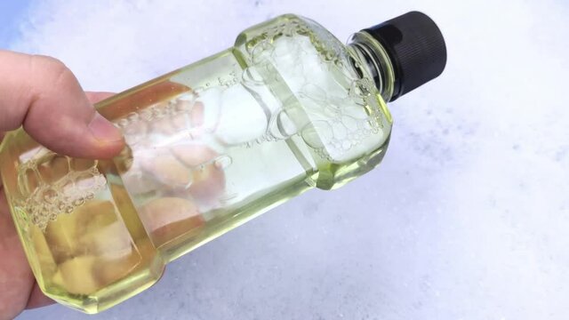 Detergent bottles float in the foam. The concept of the dangers of household chemicals. Laureate of sodium, parabens, sulfates and other chemical compounds in the composition. Mouthwash in a container