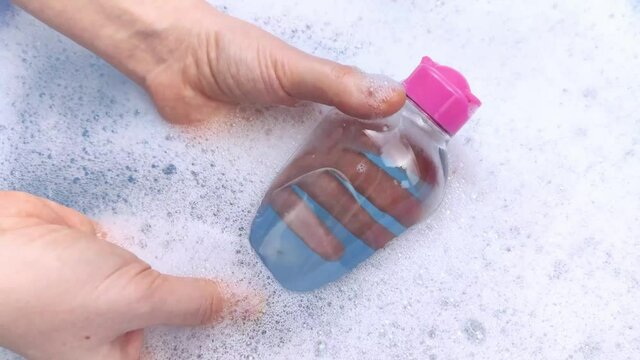 Bottles of detergents float in the foam. The concept of the dangers of household chemicals. Sodium laureate, parabens, sulfates and other hazardous chemical compounds in the foam. Micellar water