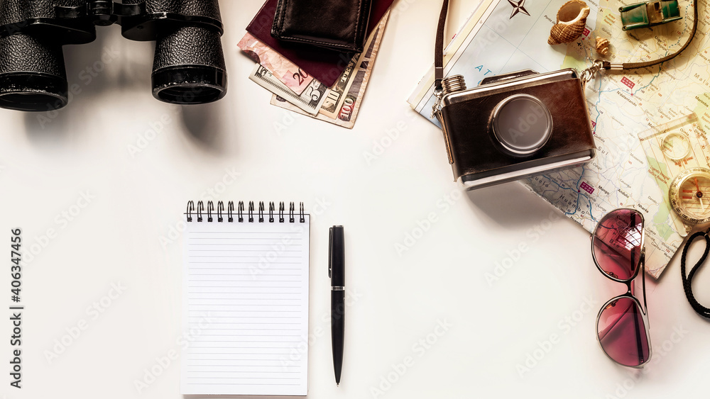 Poster top view of a pen and a notebook on the table with other traveling items