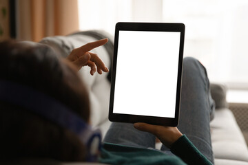 Close up back view of woman lying relaxing on sofa at home use modern tablet gadget. Female rest on...