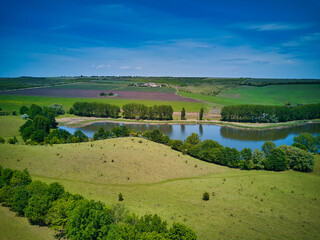 Bird's-eye view of a small pond in the middle of grain fields in the Moldova, Europe.