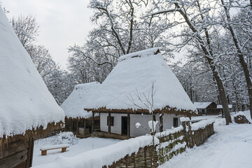 Traditional Romanian village with old house straw roofing covered with snow