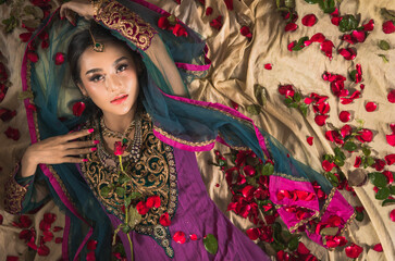 Portrait of beautiful indian girl lying with kundan jewelry set. Traditional India costume lehenga choli or sari