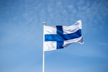 Finnish national flag on the wind against the blue sky
