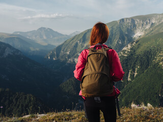 Hiker with a backpack in the mountains in nature and a pink jacket leggings