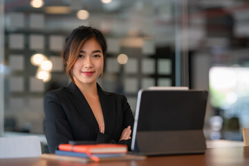 Fototapeta premium Portrait of a female entrepreneur looking into the camera while working with a computer in an office room.