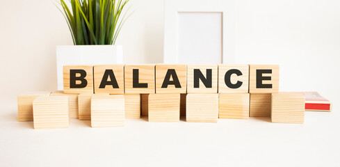 Wooden cubes with letters on a white table. The word is BALANCE. White background.