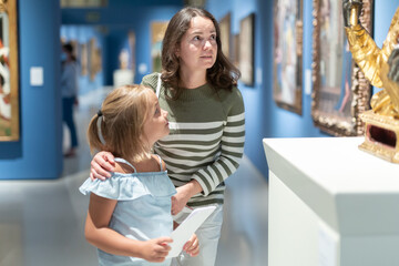 Portrait of woman with girl looking at modern painting in museum of art