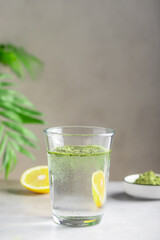 glass of water with green superfood powder. Healthy drink to support immunity and digestive health. vertical image. selective focus