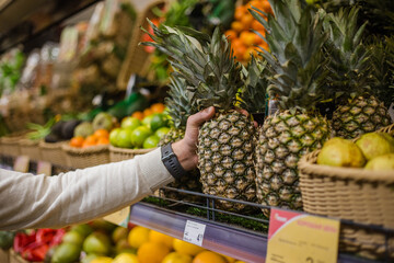 Close up of man hand choosing pineapple at grocery store