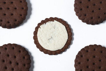 On a white background in the center lay a chocolate-cream cookie broken in half. Next to it in the corners are four whole cookies.