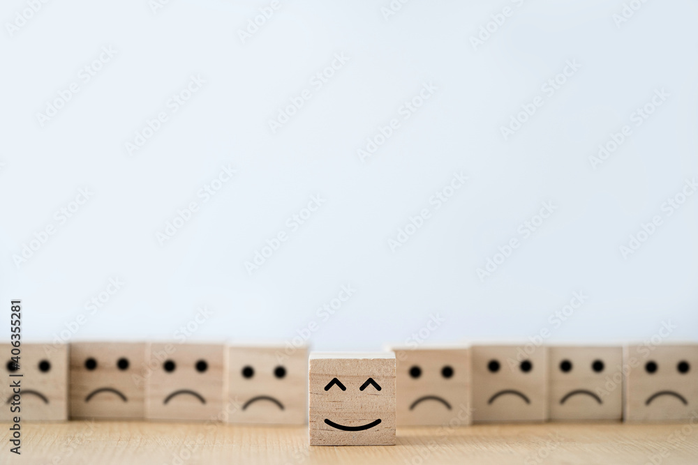 Poster Smile face print screen on wooden block cube in front of sadness face.