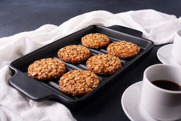 Oatmeal cookies with sesame seeds on a black cast iron pan on a white background.