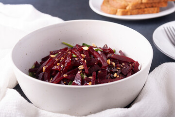 Beetroot salad with sesame seeds and olive oil on a white plate on a white plate.