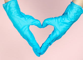 Heart from hands in medical gloves. Doctor's hands in the shape of a heart on a pink background