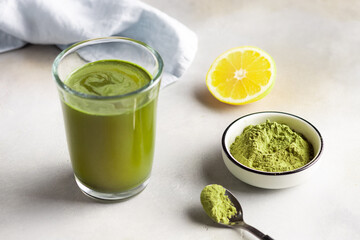 healthy energy drink and green superfood powder in bowl on table. Powder mix from wheat grass, barley grass, chlorella, spirulina, maca, matcha. detox food supplement. selective focus