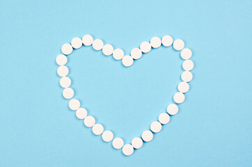 White pills in the form of a heart on a blue background