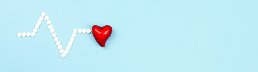 Red heart and pills in the form of a cardiogram on a blue background